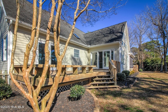 back of house with a shingled roof, a deck, and an attached garage