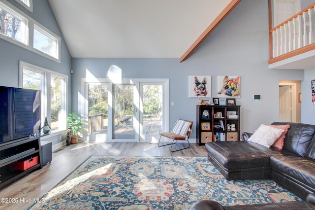 living area with high vaulted ceiling, baseboards, and wood finished floors