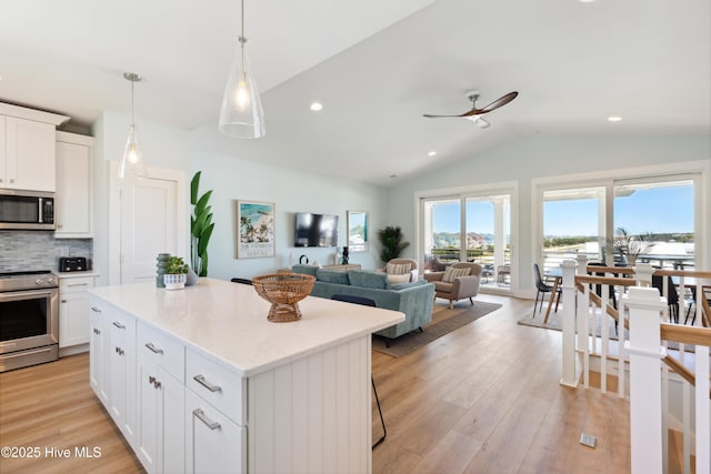 kitchen featuring a ceiling fan, appliances with stainless steel finishes, tasteful backsplash, vaulted ceiling, and light wood-type flooring
