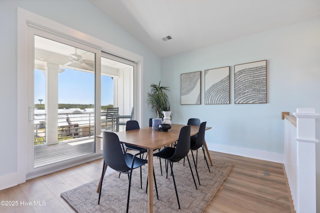 dining space featuring light wood finished floors, lofted ceiling, visible vents, ceiling fan, and baseboards