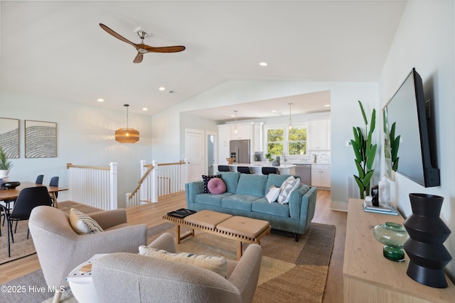 living room featuring a ceiling fan, vaulted ceiling, recessed lighting, and light wood-style flooring