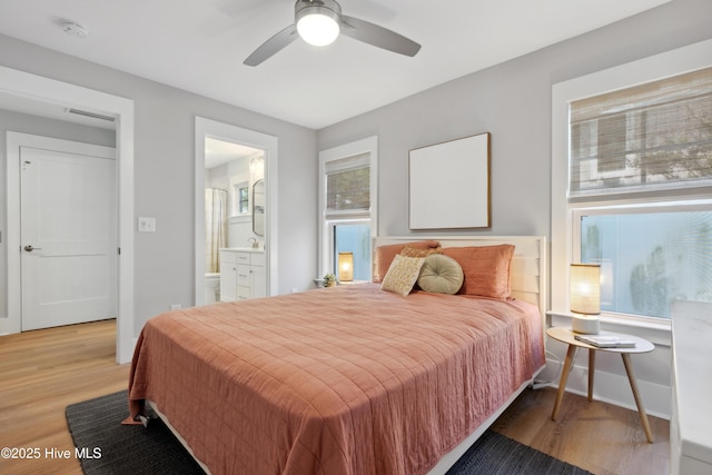 bedroom featuring visible vents, ceiling fan, ensuite bath, wood finished floors, and baseboards