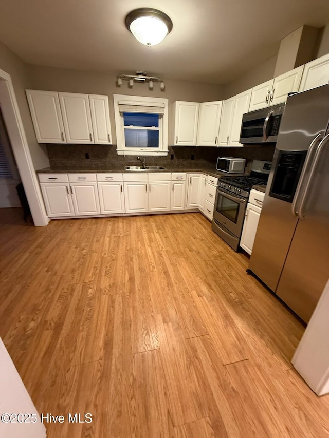 kitchen with white cabinetry, appliances with stainless steel finishes, sink, and light hardwood / wood-style floors