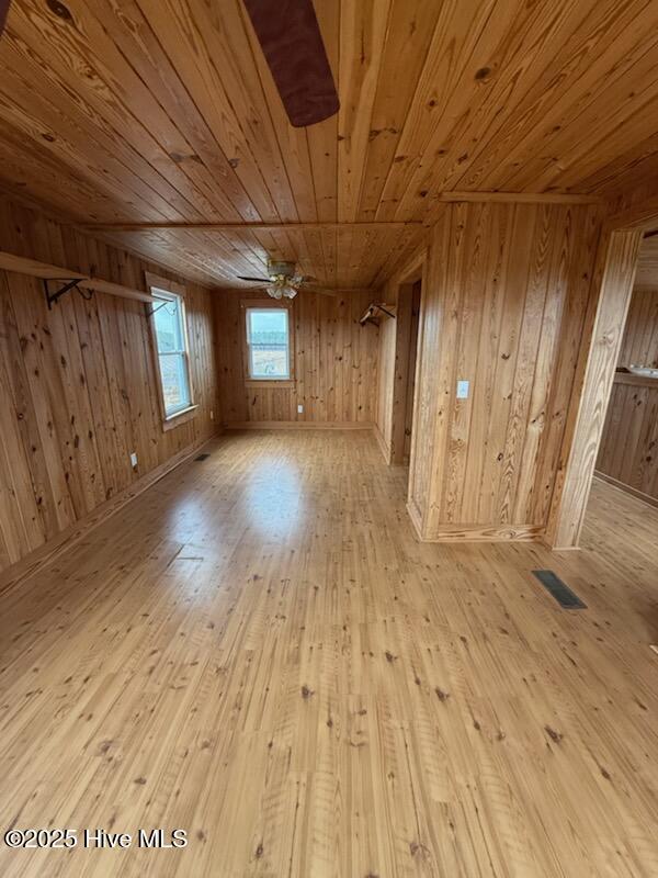 additional living space with wooden ceiling, wooden walls, and light hardwood / wood-style flooring