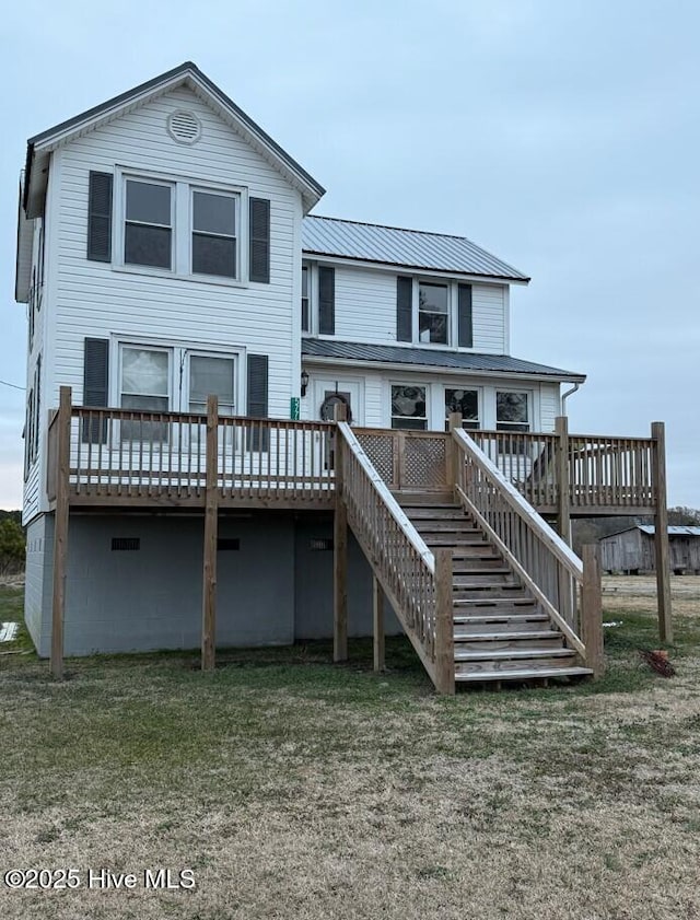 back of property featuring a wooden deck and a lawn