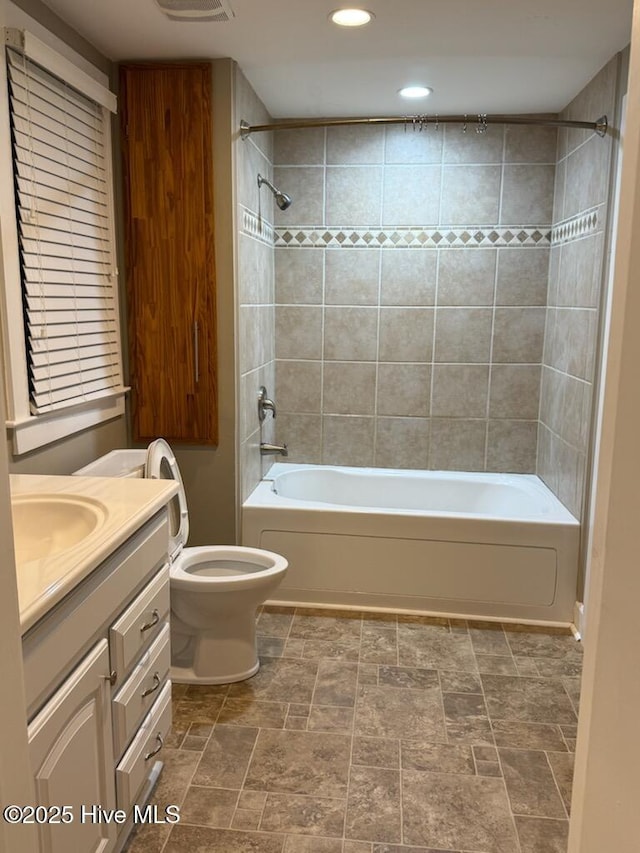 full bathroom with tiled shower / bath combo, vanity, and toilet