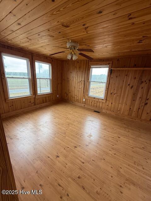 interior space featuring wood ceiling, wooden walls, ceiling fan, and light wood-type flooring