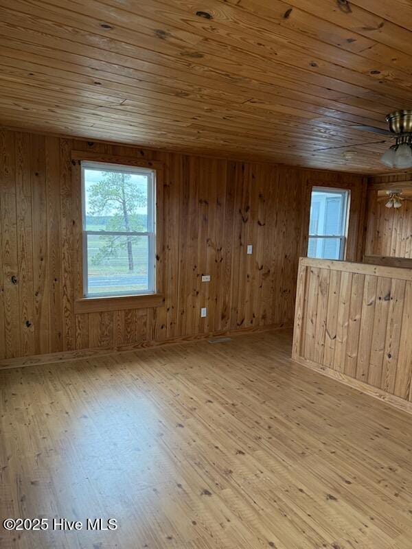 spare room with wood ceiling, wood walls, and light wood-type flooring