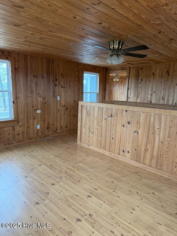 spare room with ceiling fan, wooden walls, wood ceiling, and light wood-type flooring