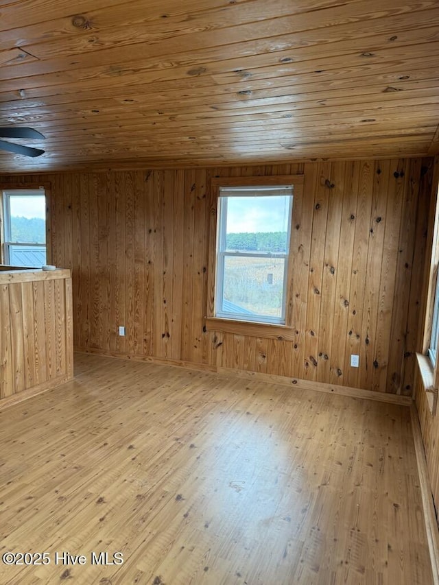 unfurnished room with wooden walls, wooden ceiling, and light wood-type flooring