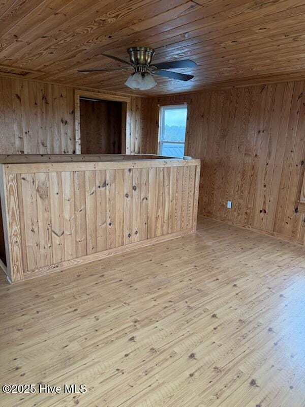 spare room with wood ceiling, wooden walls, light hardwood / wood-style floors, and ceiling fan