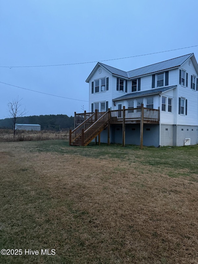 rear view of property with a wooden deck and a lawn