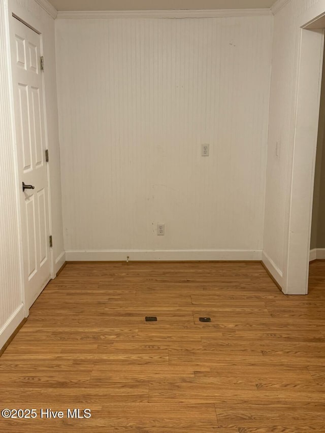 spare room featuring crown molding and light hardwood / wood-style floors