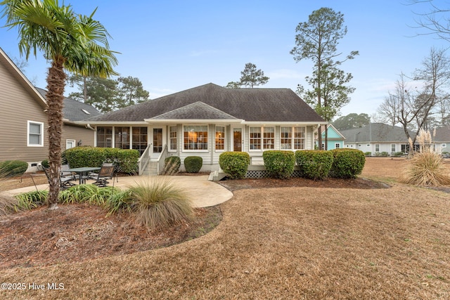 rear view of house with a sunroom, a patio, and a lawn