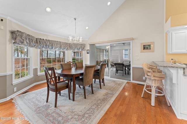 dining space featuring a chandelier, high vaulted ceiling, and light hardwood / wood-style flooring