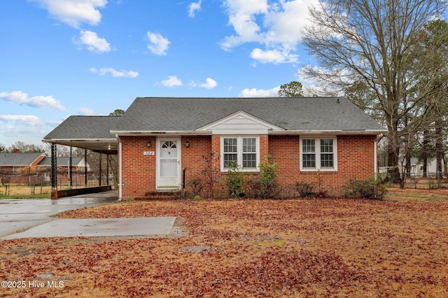 view of front of house with a carport, brick siding, fence, and driveway