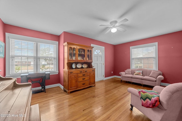 living room featuring light wood-style floors, ceiling fan, and baseboards