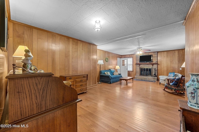 living area with a fireplace, light wood-style flooring, and ceiling fan