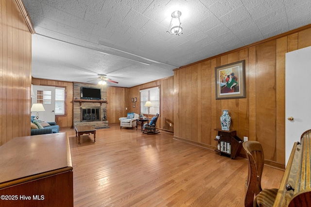 living area with light wood finished floors, a fireplace, and a ceiling fan