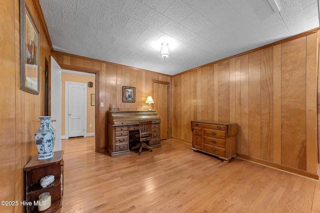 office space featuring crown molding, wood walls, wood finished floors, and baseboards