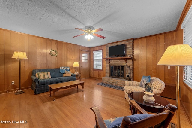 living room featuring ceiling fan, wood walls, a fireplace, and wood finished floors