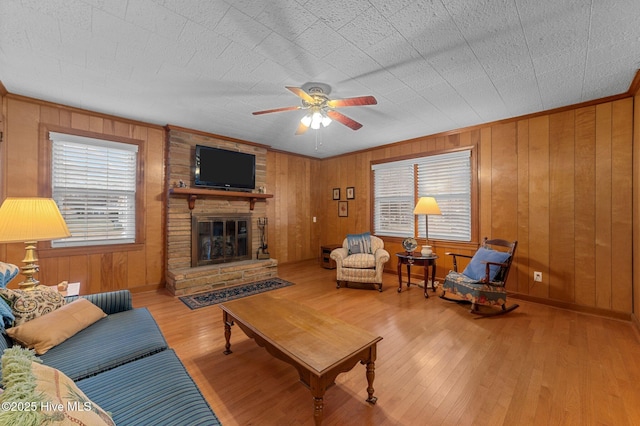 living room with ceiling fan, a large fireplace, plenty of natural light, and wood finished floors