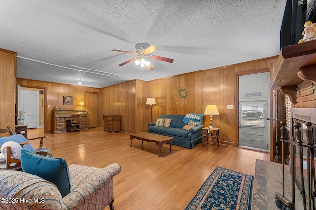 living area featuring ceiling fan, a fireplace, and wood finished floors