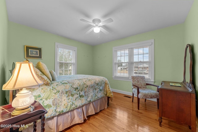 bedroom featuring a ceiling fan, light wood-type flooring, visible vents, and baseboards