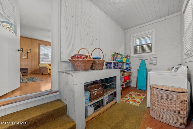 clothes washing area with brick wall, laundry area, plenty of natural light, and washing machine and clothes dryer