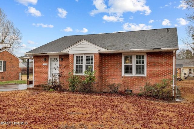 bungalow featuring brick siding and roof with shingles