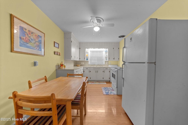 dining area with light wood-type flooring and a ceiling fan