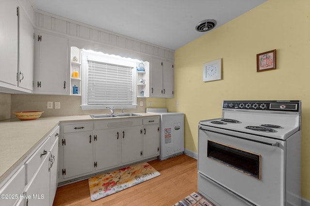 kitchen featuring white range with electric stovetop, light wood finished floors, light countertops, visible vents, and a sink