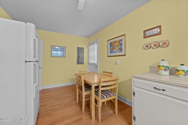 dining space featuring ceiling fan, light wood-type flooring, electric panel, and baseboards