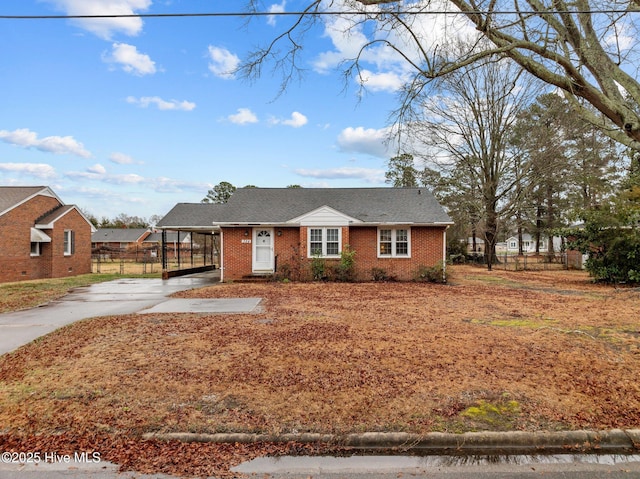 view of front of home with a carport, concrete driveway, brick siding, and fence