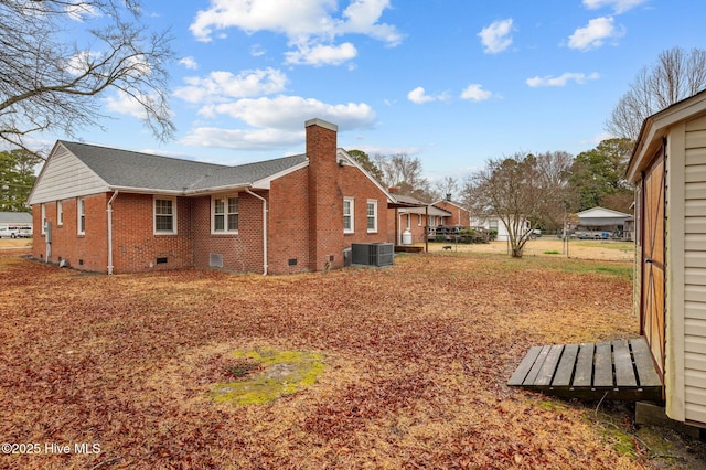 view of home's exterior featuring a shingled roof, a chimney, crawl space, central air condition unit, and brick siding