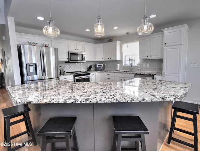 kitchen featuring light wood-type flooring, tasteful backsplash, white cabinetry, and stainless steel appliances