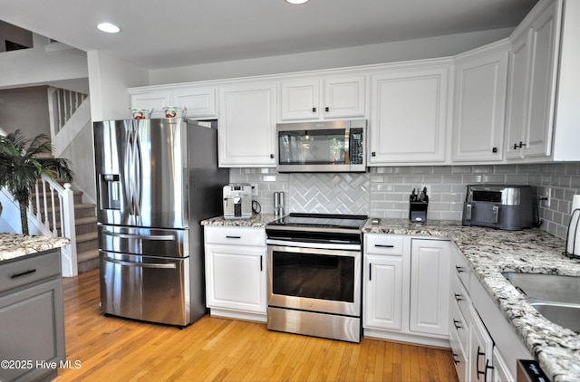 kitchen featuring stainless steel appliances, light wood-type flooring, and white cabinetry