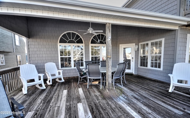 wooden deck featuring outdoor dining area and a ceiling fan