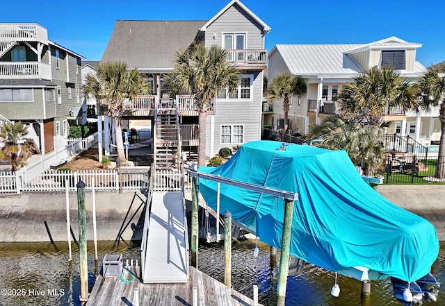 dock area featuring a water view, fence, and stairs