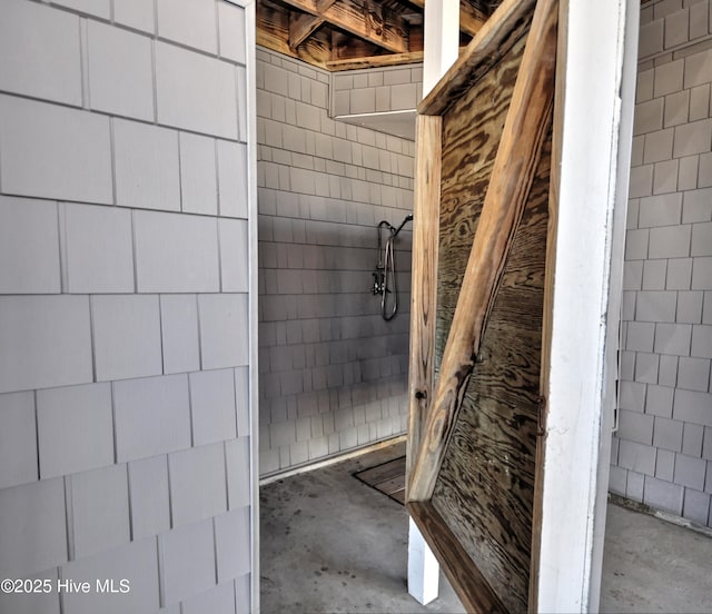 bathroom with a tile shower and concrete flooring