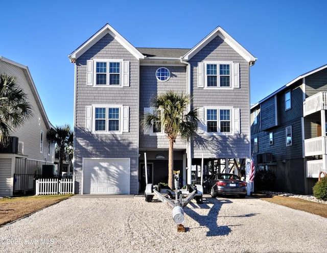 view of front of property with a garage, a carport, gravel driveway, and fence