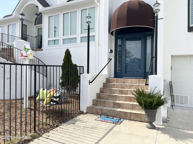 property entrance featuring stucco siding, visible vents, and fence