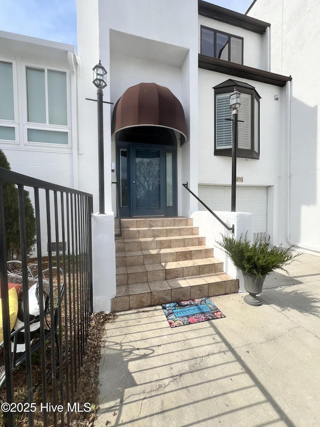 entrance to property with a garage and stucco siding