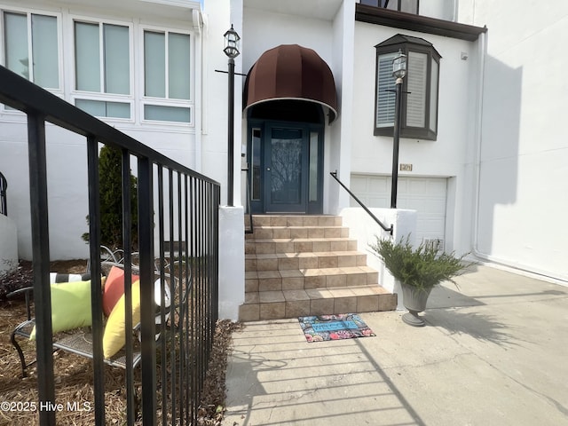 entrance to property with a garage and stucco siding