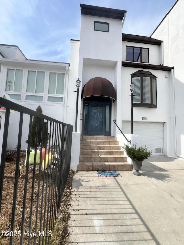 property entrance with concrete driveway, an attached garage, and stucco siding