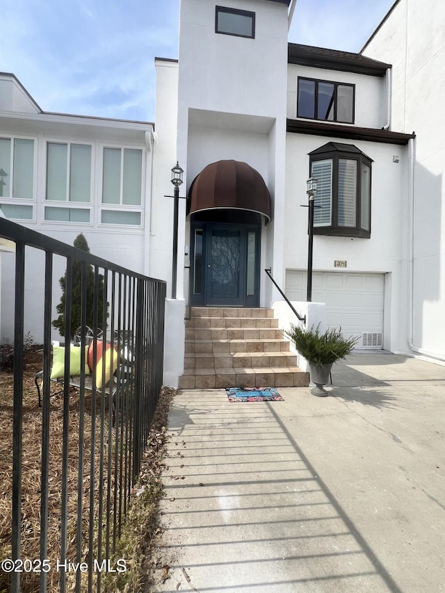 property entrance featuring an attached garage, driveway, and stucco siding