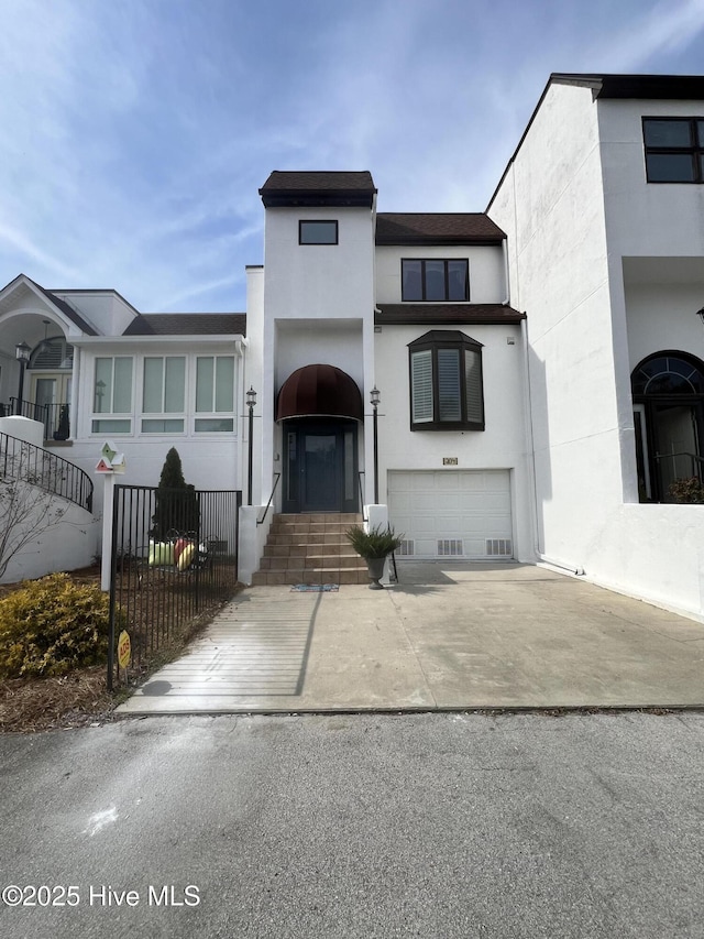 view of front of home with a garage, roof with shingles, a fenced front yard, and stucco siding