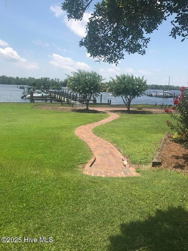 surrounding community with a water view and a lawn