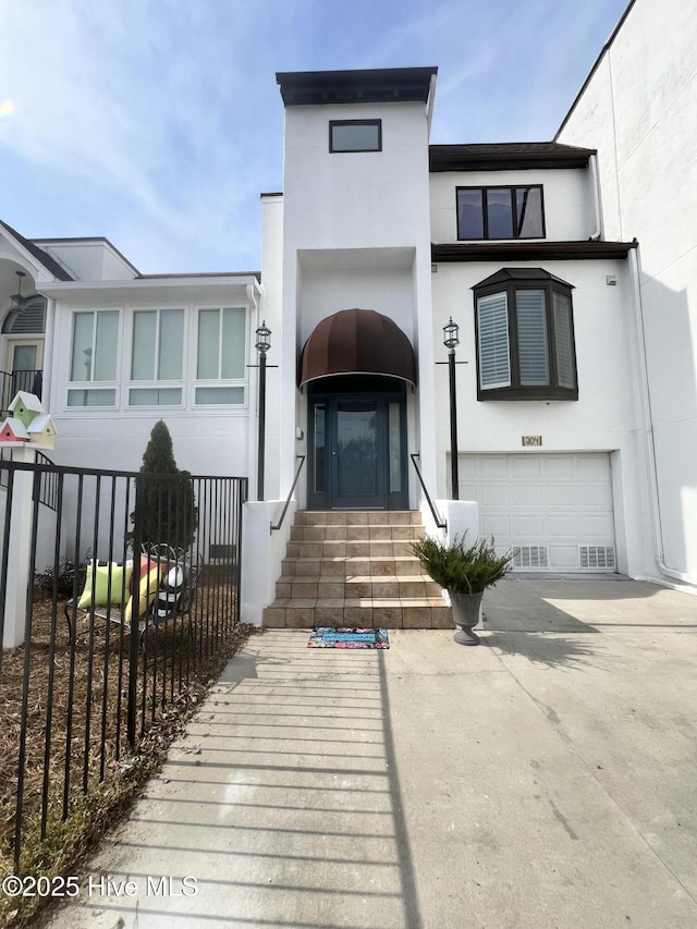 view of front of home featuring stucco siding, driveway, a garage, and fence