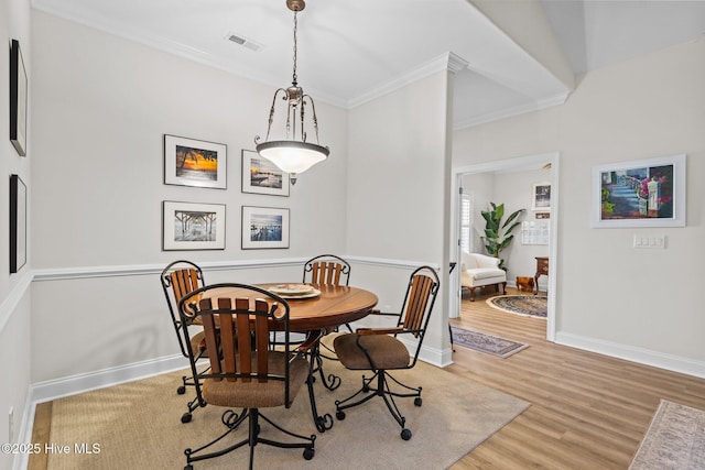 dining area featuring ornamental molding, visible vents, baseboards, and wood finished floors